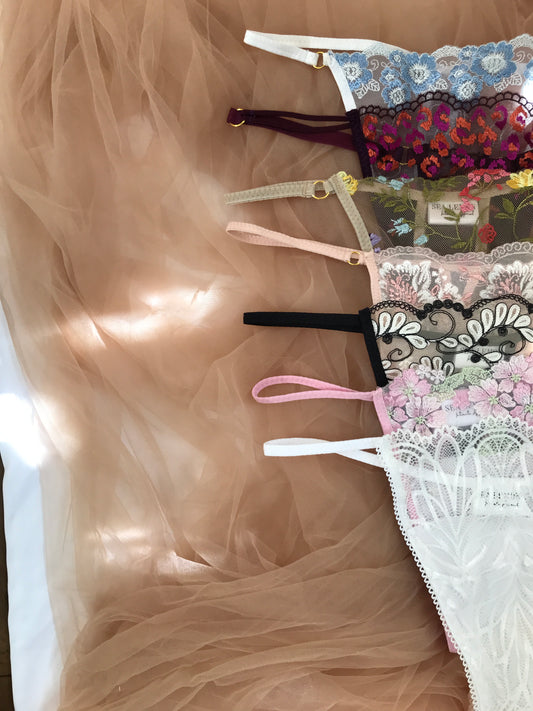 A collection of colorful g-strings laid out on a neutral fabric, showcasing a variety of patterns and colors.