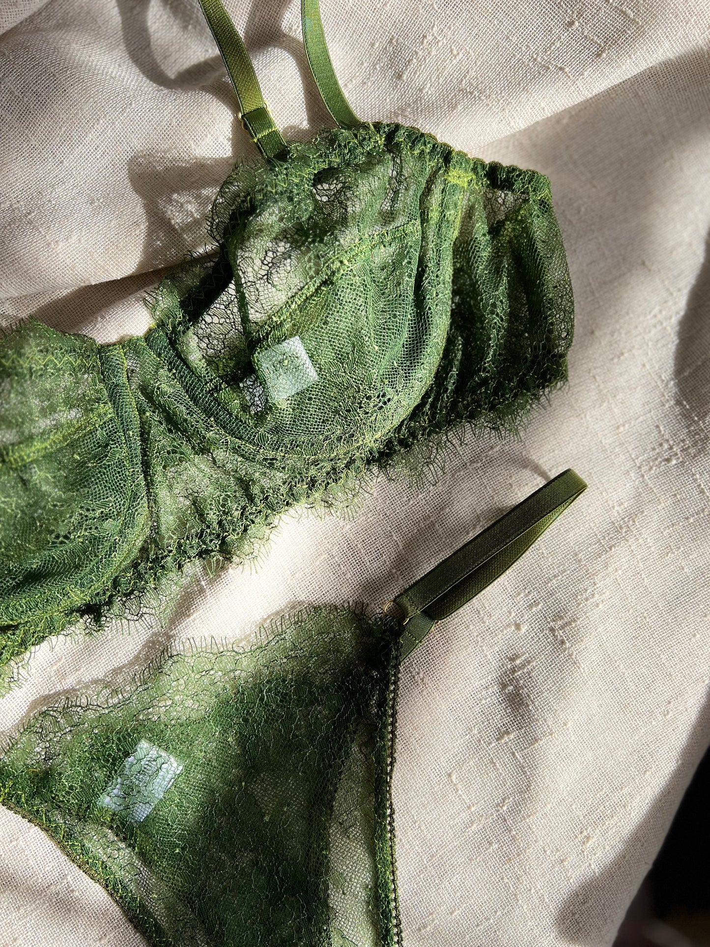 Green lace bra and panties set on a textured beige surface
