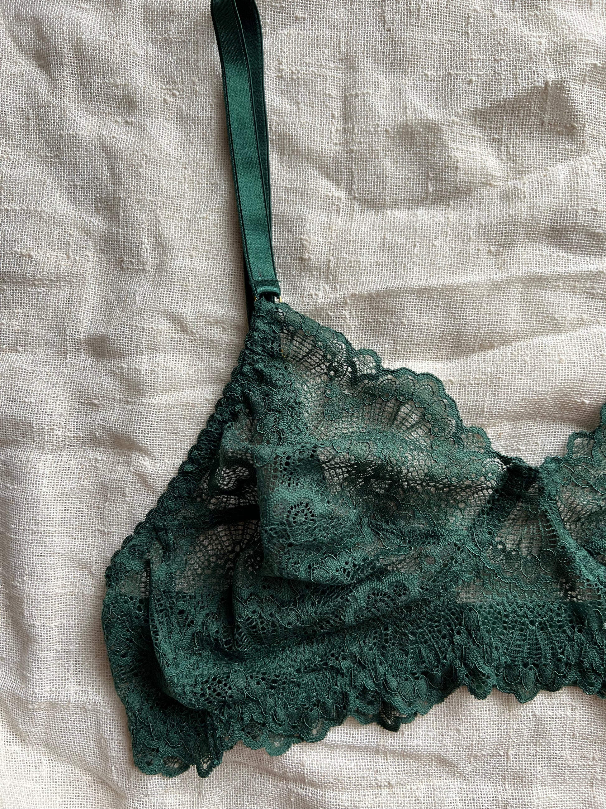 Green lace bra on a textured beige fabric background