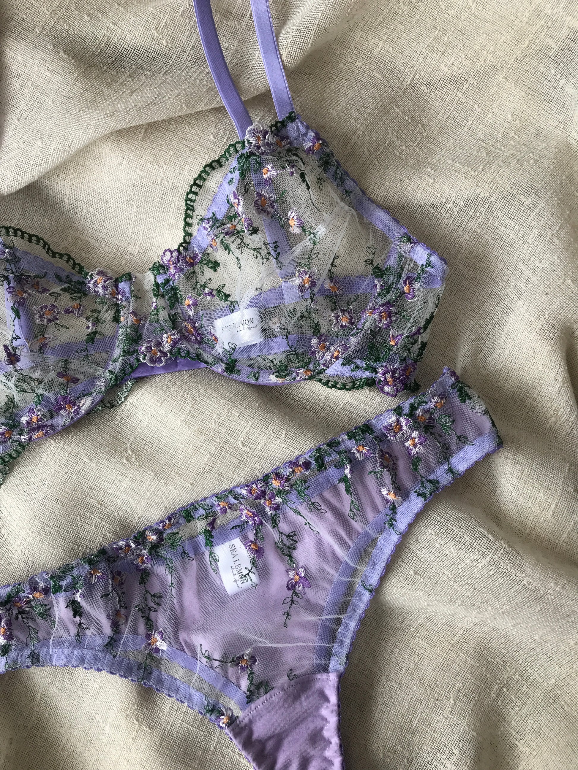 Purple floral lingerie set on a beige fabric background
