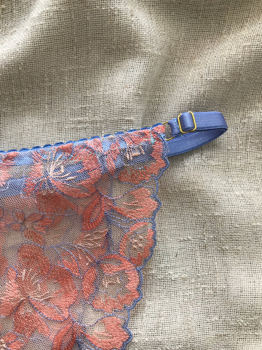 Floral patterned bikini with a blue strap on a textured fabric background