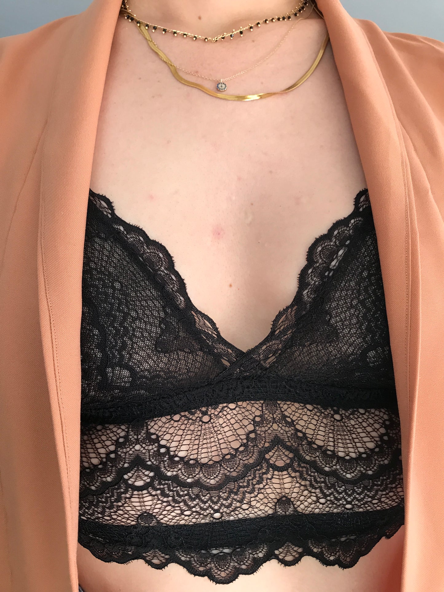 Close-up of a person wearing a beige top with black lace detailing.