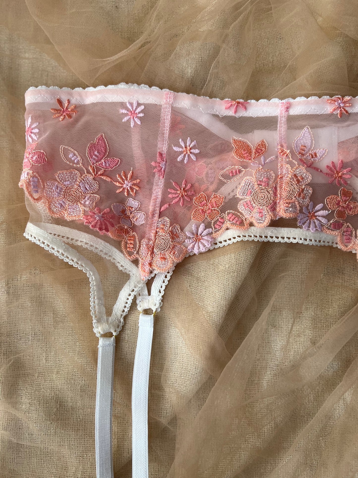 Floral embroidered lingerie set on a beige fabric background