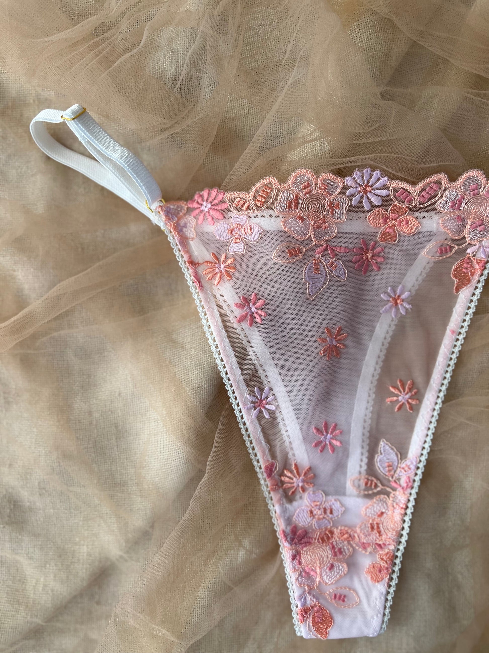 Lace thong with floral embroidery on a beige fabric background