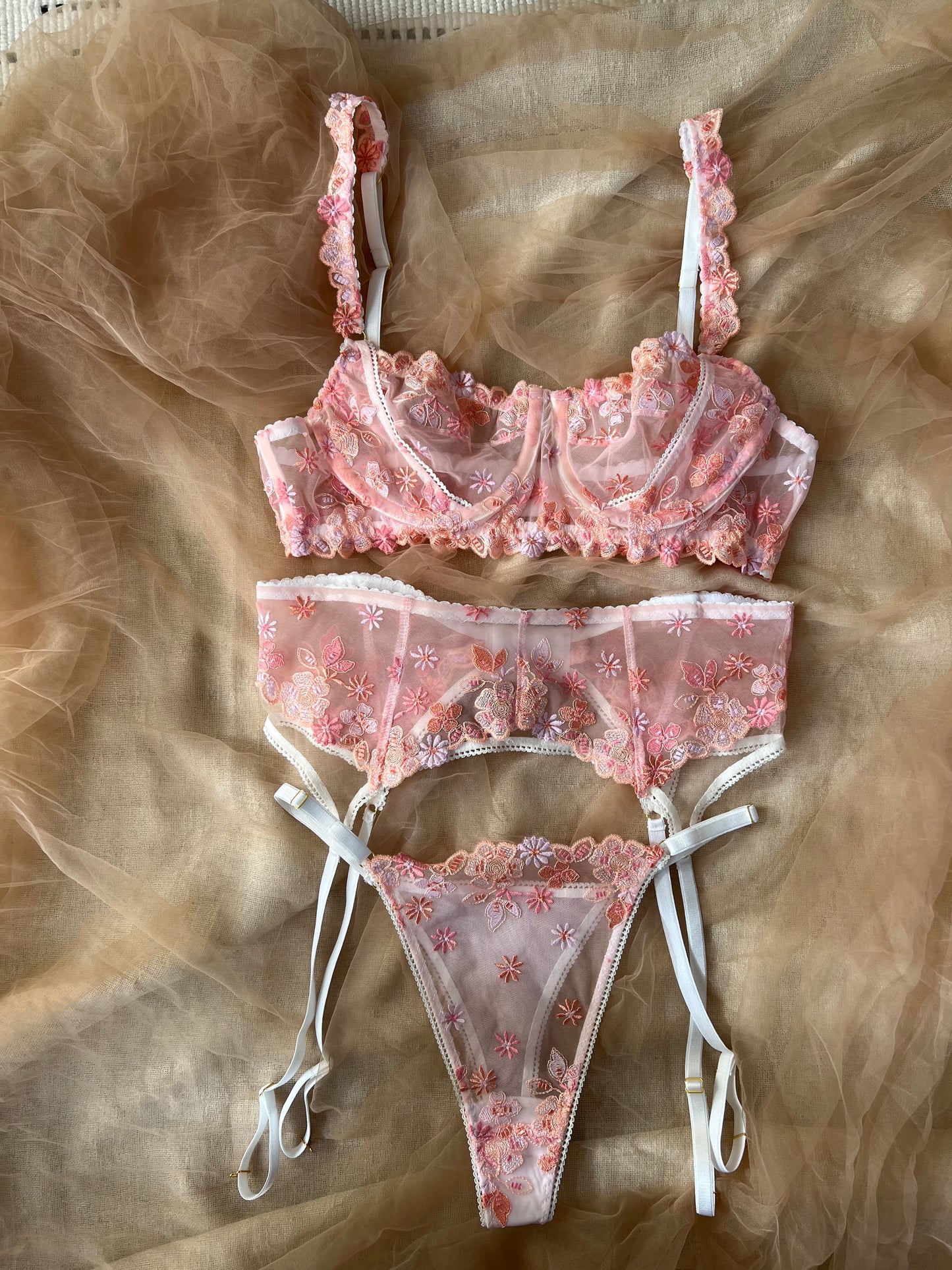 Pink lace lingerie set on a sheer fabric background