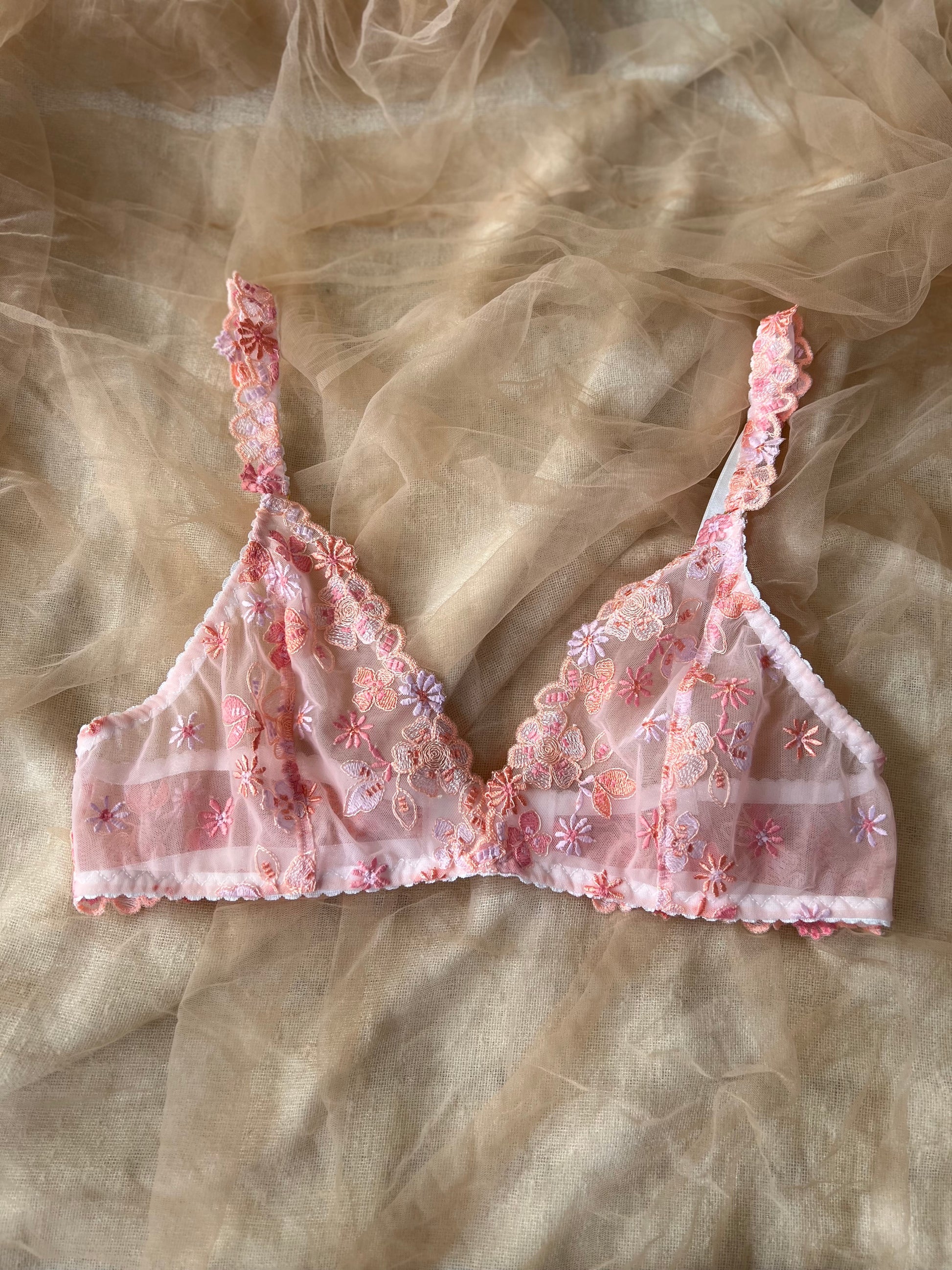 Pink floral embroidered bralette on a sheer fabric background