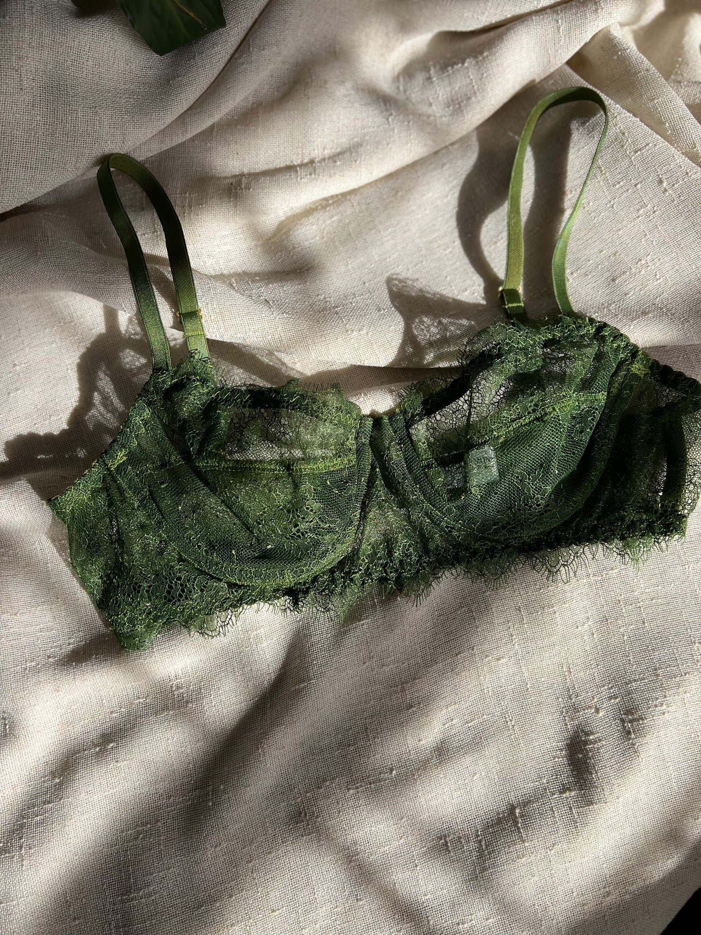 Green bralette on a textured beige fabric background
